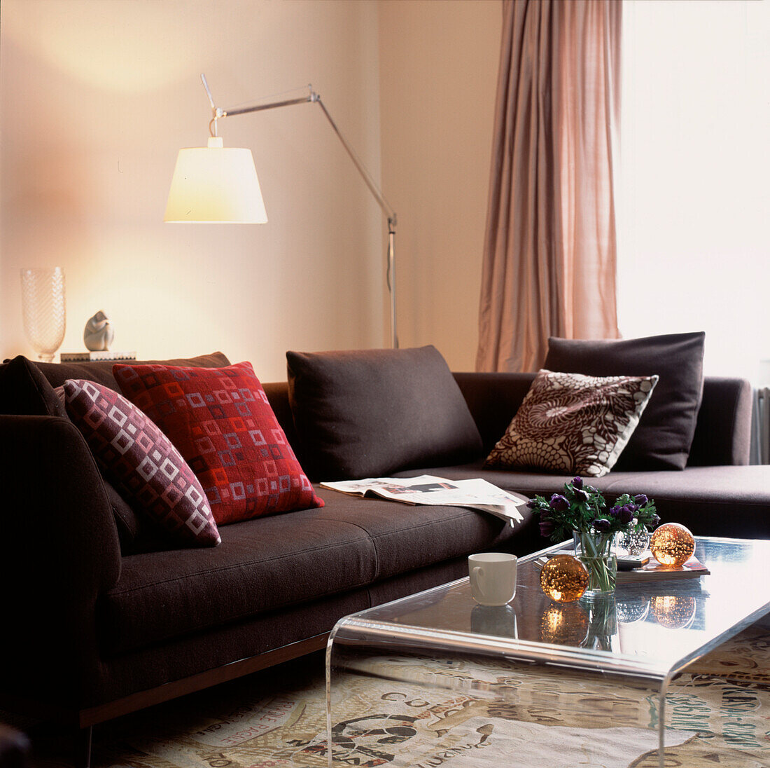 Modernes Wohnzimmer mit großem braunen Ecksofa in L-Form mit Kissen, Leselampe und Couchtisch aus Plexiglas