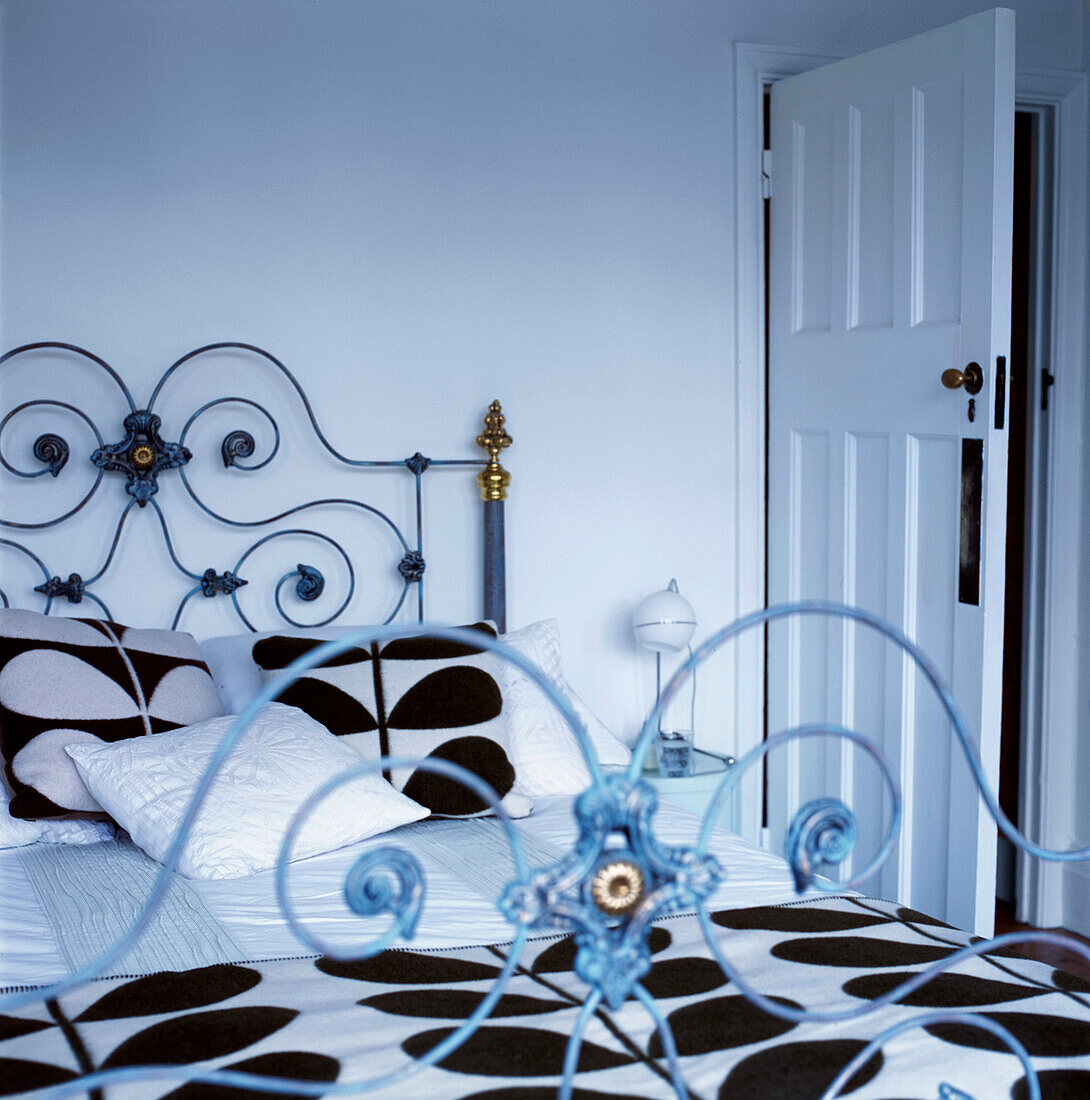 White bedroom with vintage style ornate double bed with bold patterned black and white bed linen