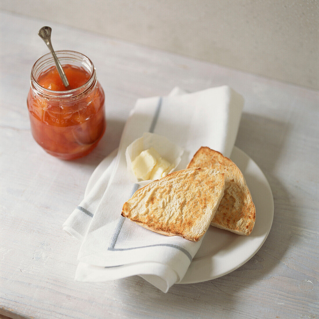 Jar of jam with white toasted bread and butter