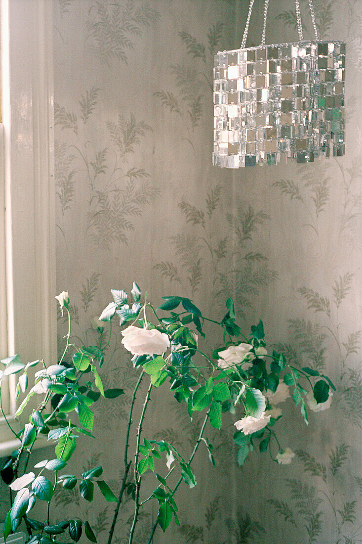Wohnzimmer mit Metallblumentapete, dekorativer Hängelampe und einem Rosenstrauch