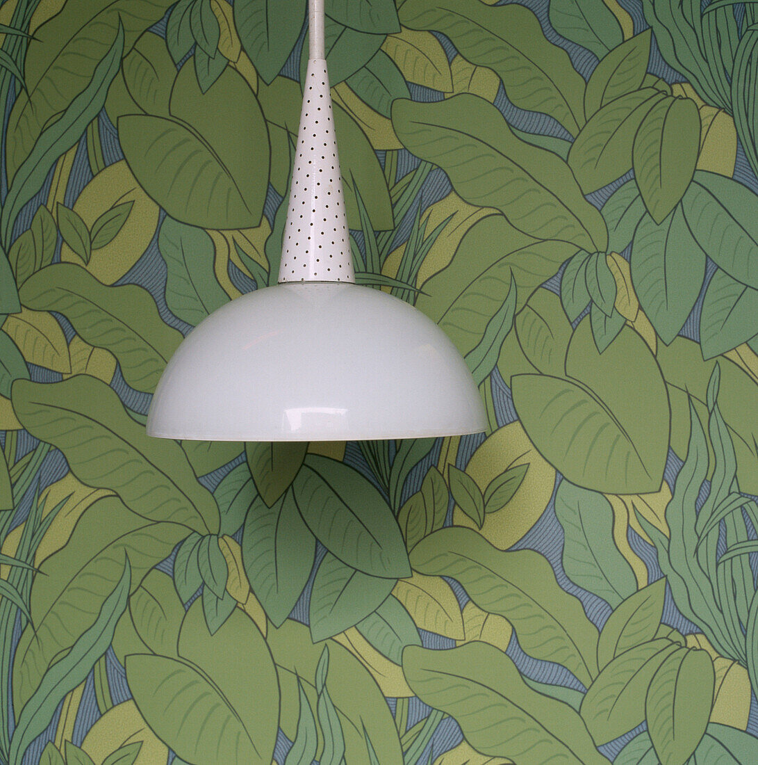 Green patterned wallpaper with a white hanging light
