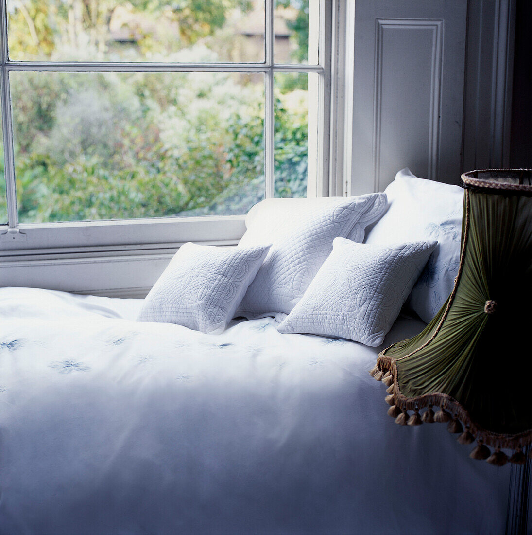 Einzelbett mit frischer weißer Bettwäsche neben einem Fenster