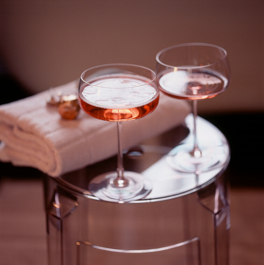 Two glasses of pink champagne on a stool in a bathroom