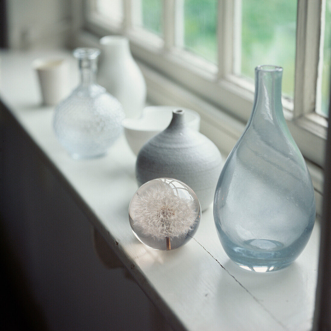 Sammlung von Haushaltswaren aus Glas und Keramik auf einer Fensterbank