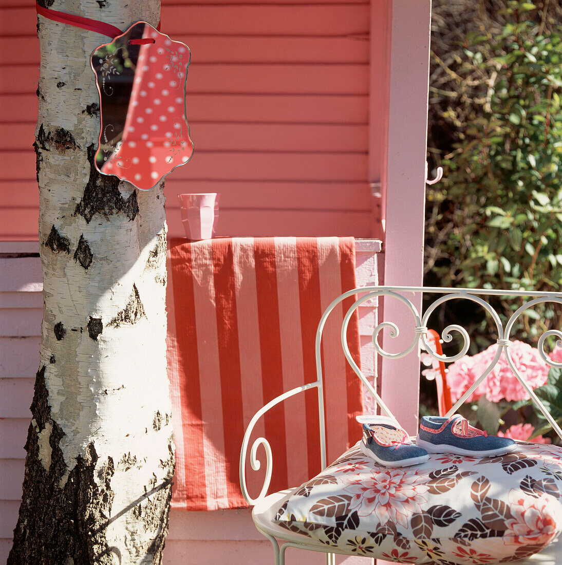 Rosa gestrichene Gartenlaube mit Gartenmöbeln auf einer Terrasse