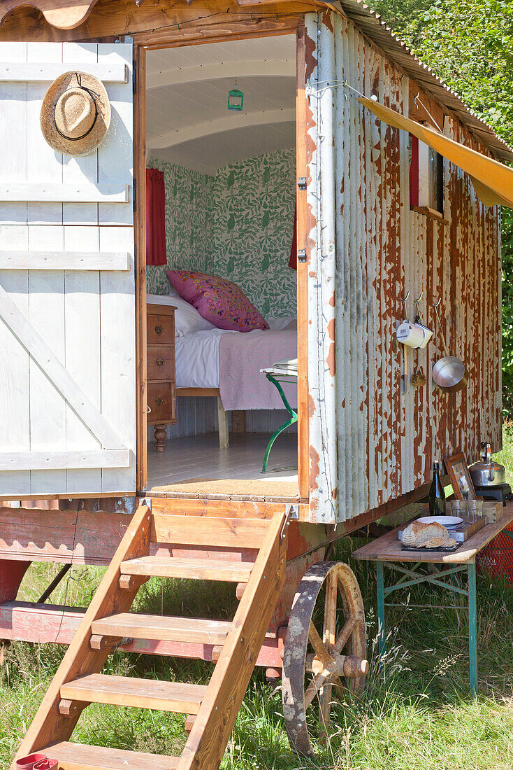 View through door of Shepherds hut into bedroom with wallpaper