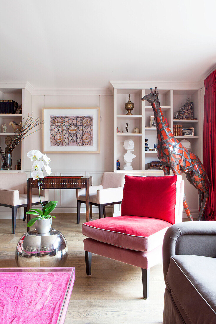 Roter Samtstuhl mit großer Giraffenstatue im Wohnzimmer einer modernen Londoner Wohnung England UK