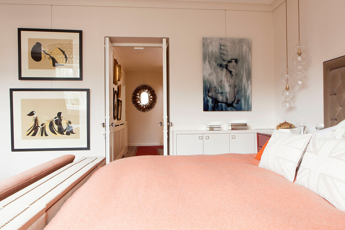 Artwork display with peach blanket on bed in contemporary London home England UK