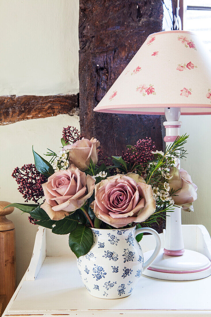 Geschnittene Rosen und Lampe auf dem Nachttisch in einem Fachwerk-Bauernhaus in Surrey, England UK