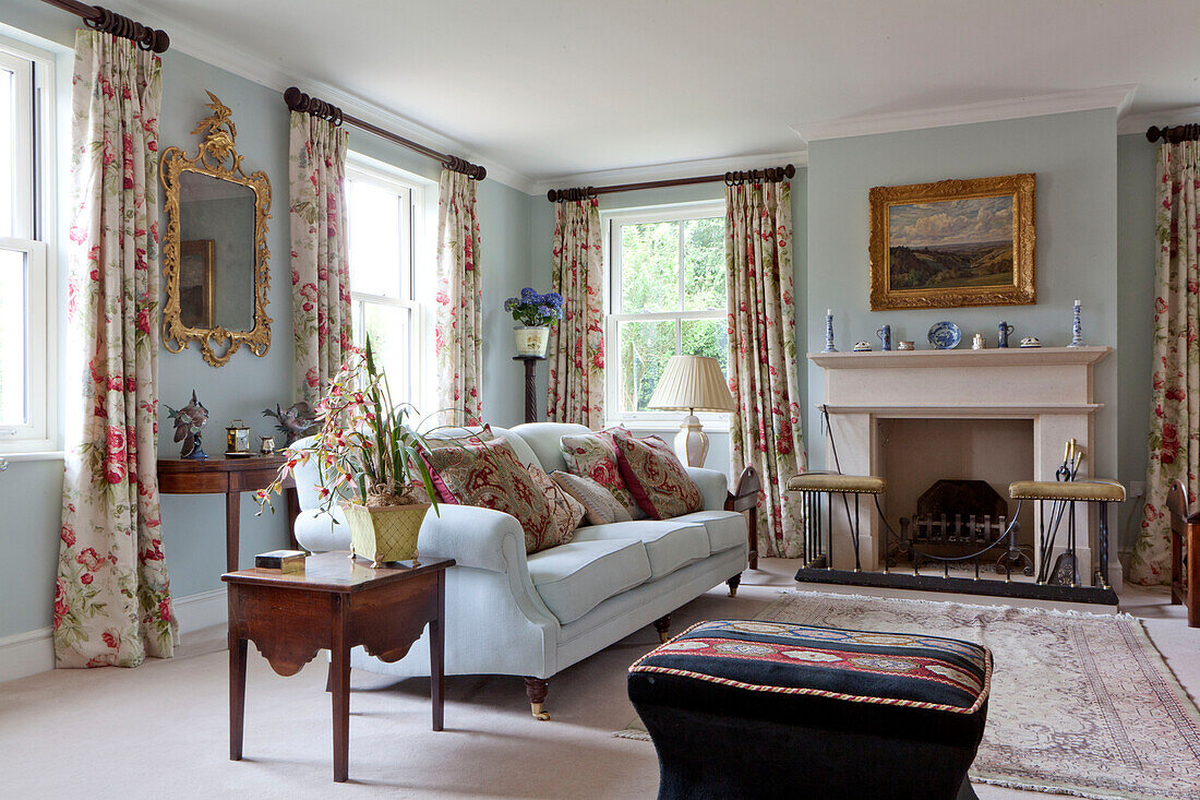 Light blue sofa with floral curtains in living room of Wiltshire country house England UK