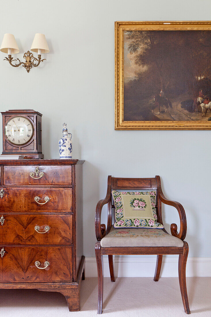 Polierte Holzstühle und Schubladen mit goldgerahmten Kunstwerken in einem Landhaus in Wiltshire, England, UK