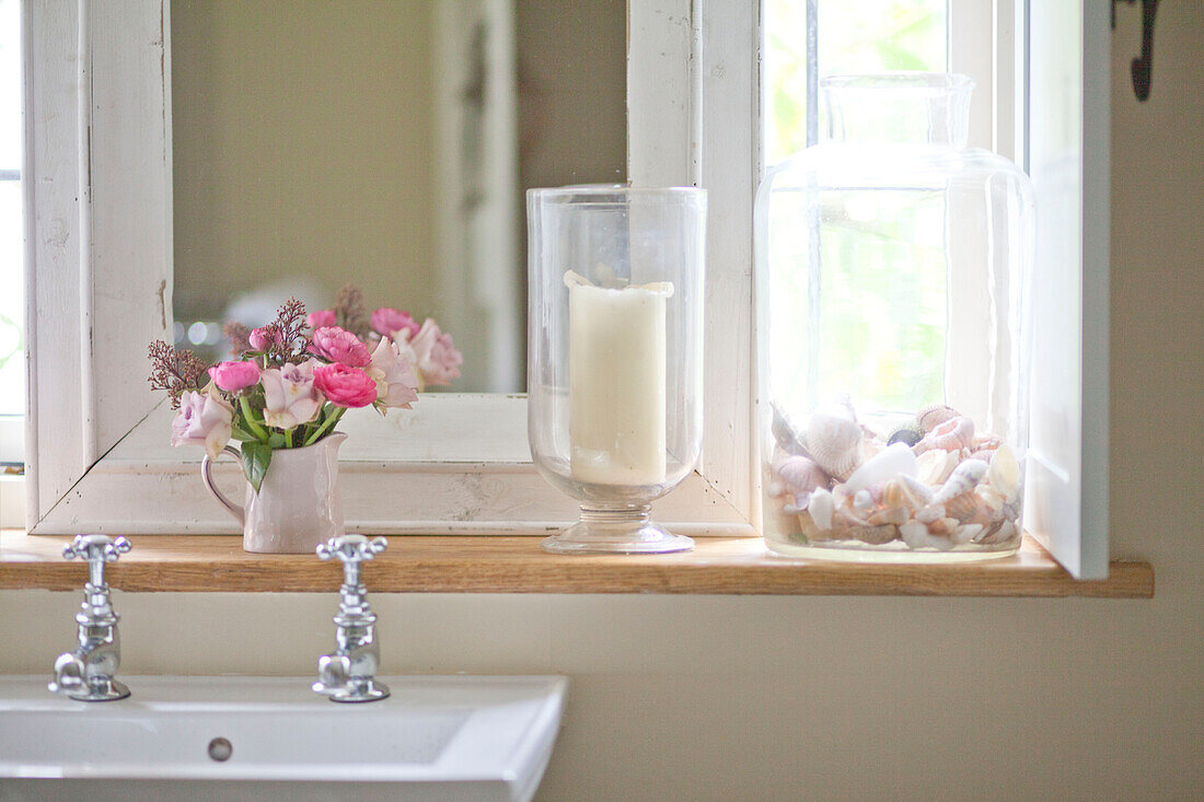 Pink roses on wooden windowsill above sink in bathroom of Surrey cottage England UK