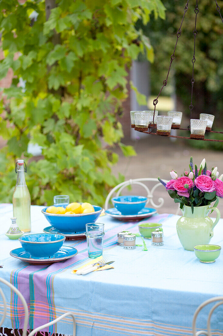 Schnittblumen und Kerzenständer auf einem Tisch auf der Terrasse eines Hauses in Surrey, England UK