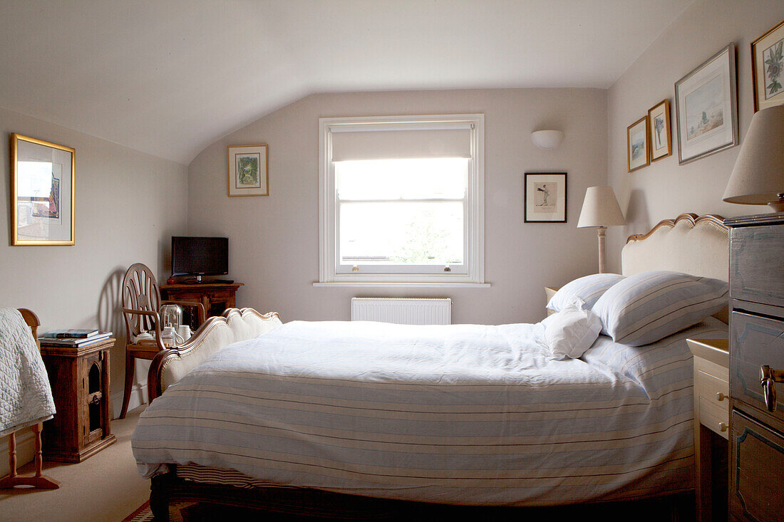 Gestreifte Bettdecke und Kissen in einem Zimmer mit Rollo am Fenster in einem modernen Haus in Chelsea, London, UK