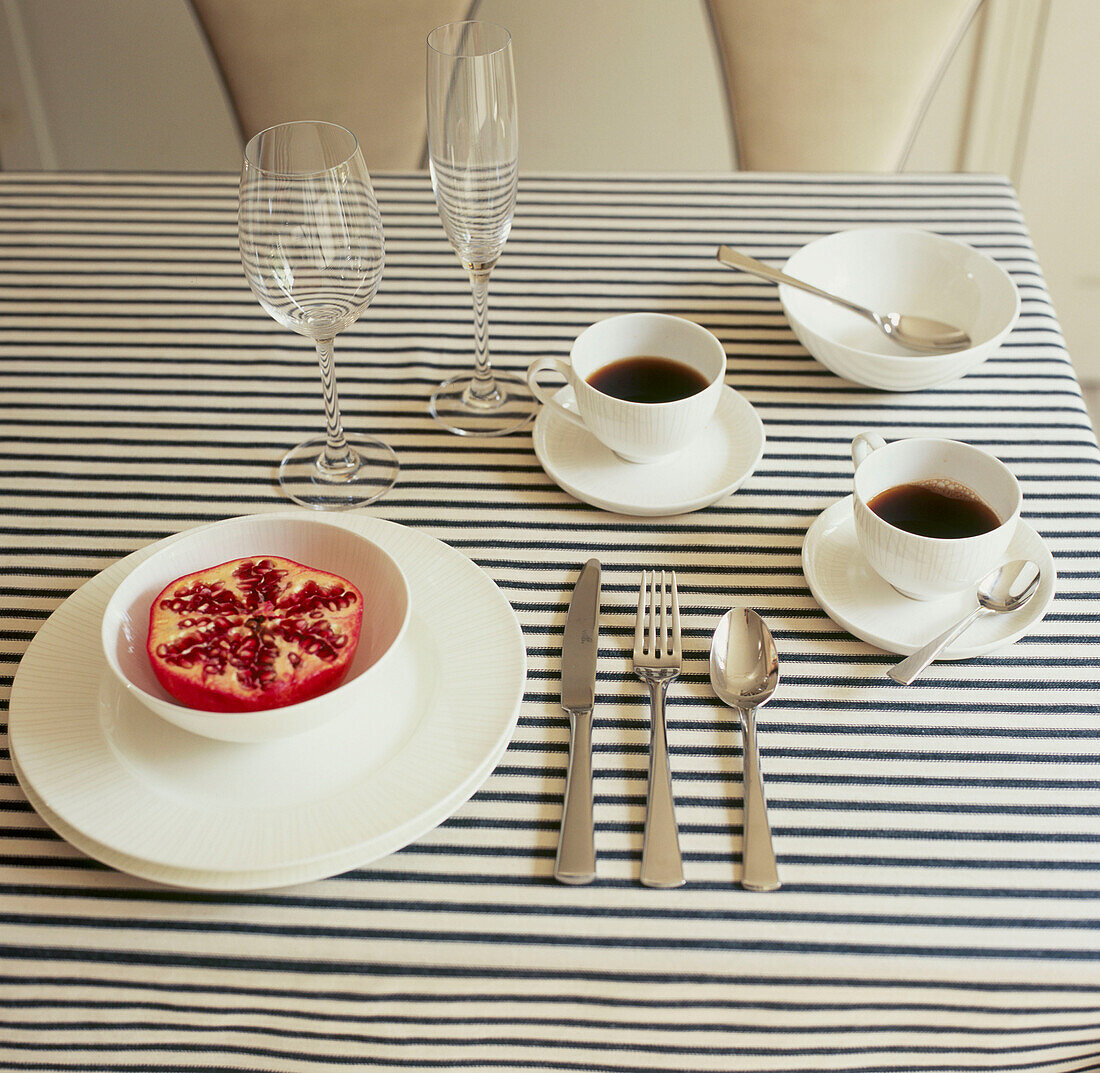 Overhead view of table setting with white tableware and striped tablecloth