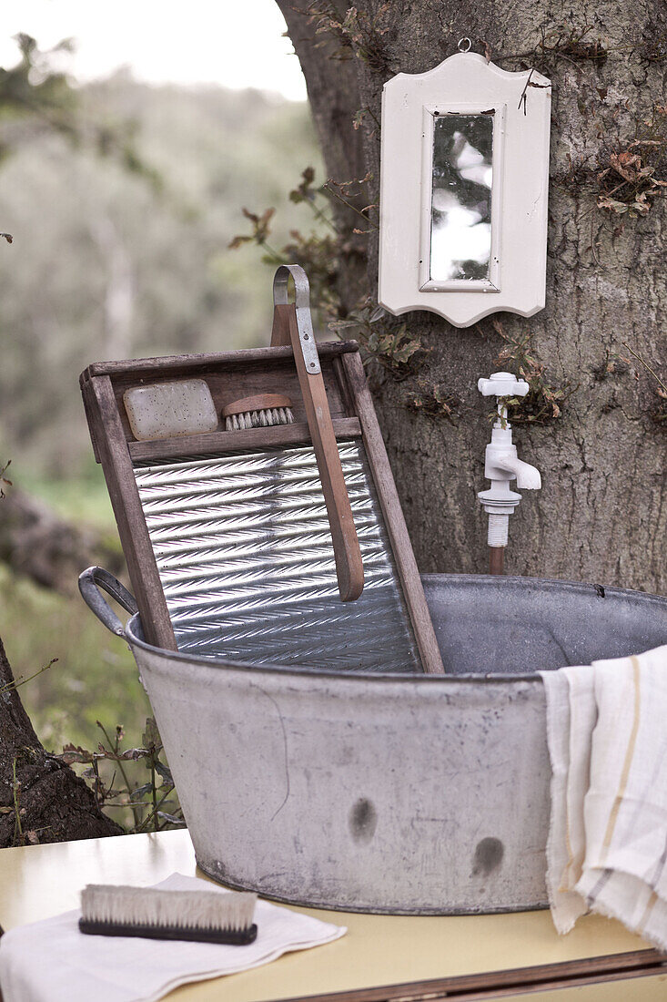Behelfsmäßiger Waschtisch und Waschbrett mit Spiegel, montiert auf einem Baumstamm, UK