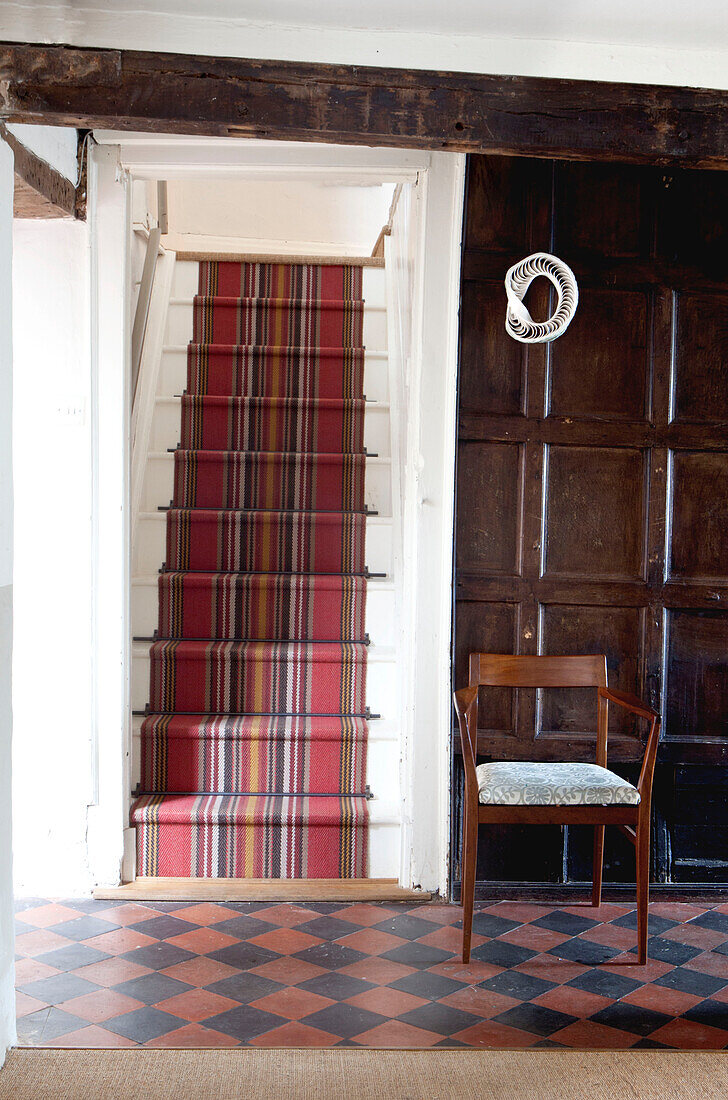 Teppichboden im Treppenhaus mit dunkler Holzvertäfelung und kariertem Boden, UK