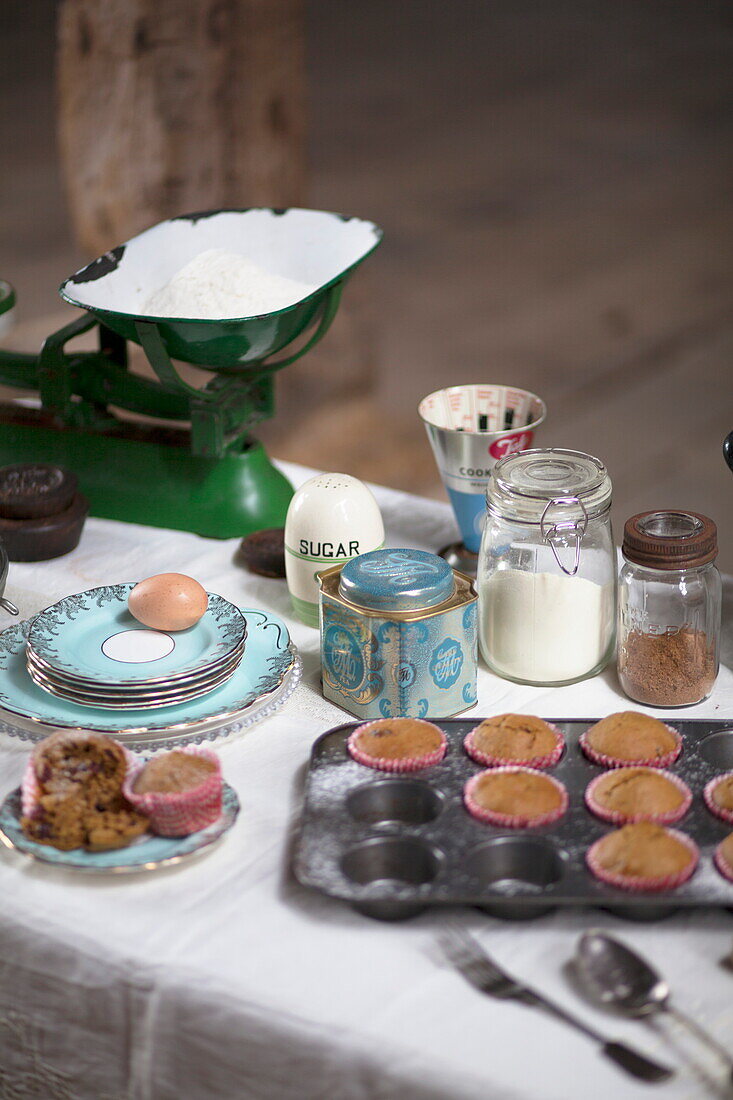 Baking ingredients and cupcakes on white tablecloth in rustic interior, United Kingdom