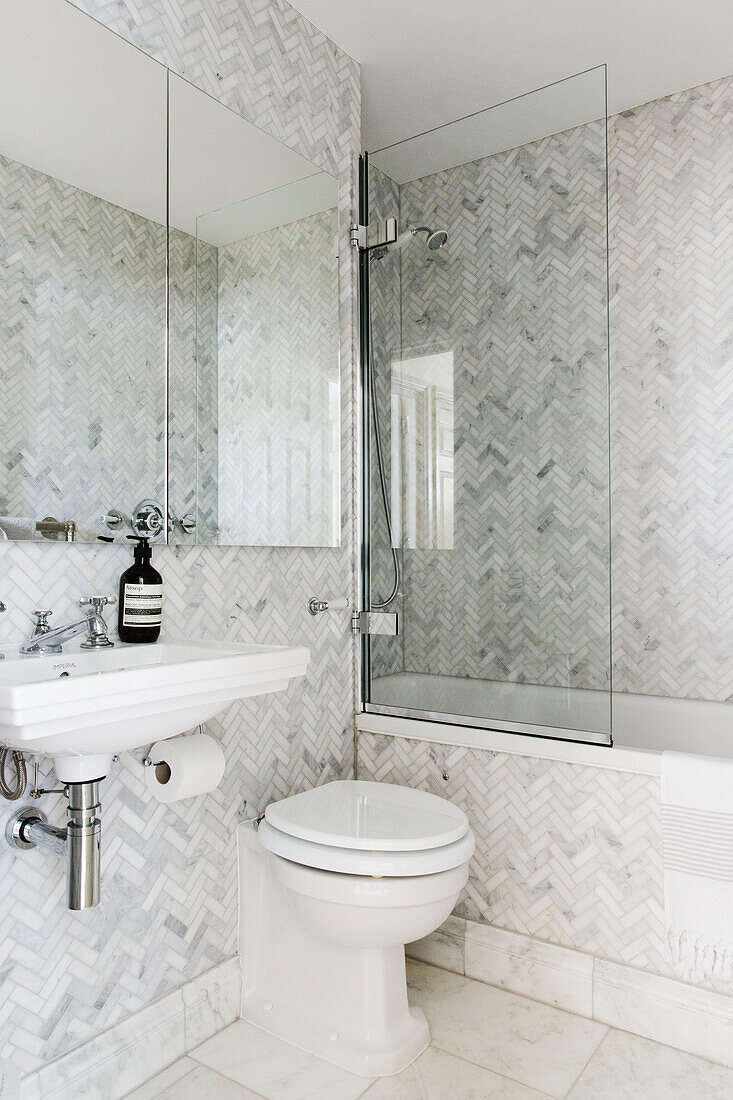 Light grey tiling and shower screen with mirrored cabinet in London bathroom UK