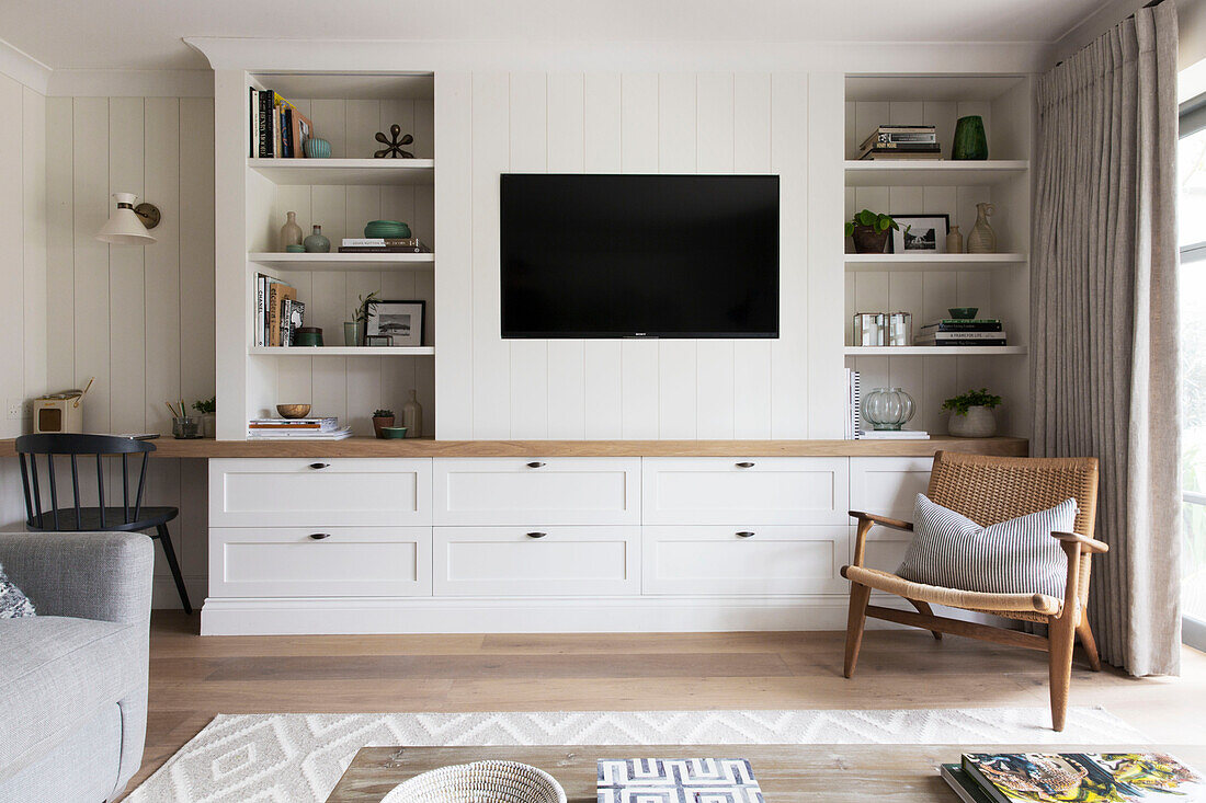 1960s style chair and shelves with wall mounted TV in London home UK