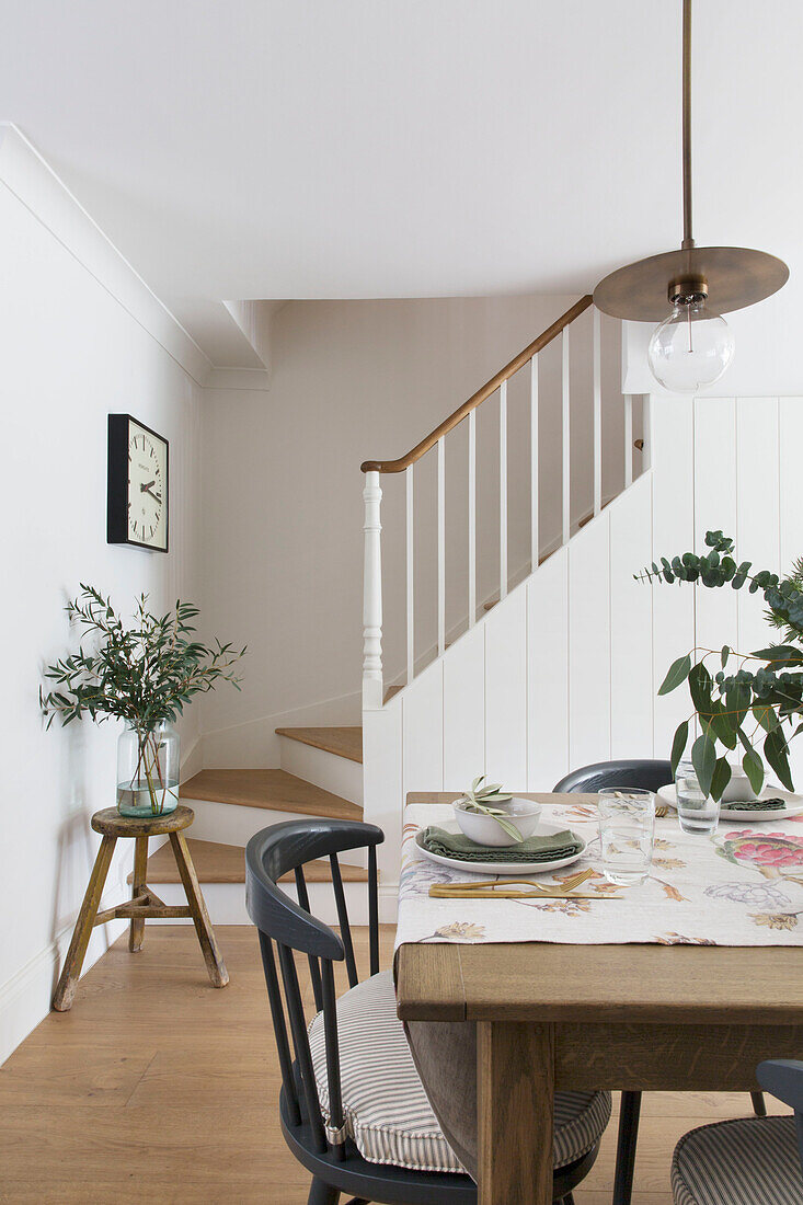 Schwarzer Stuhl am Tisch mit Läufer und offenem Treppenhaus in einem Londoner Haus UK