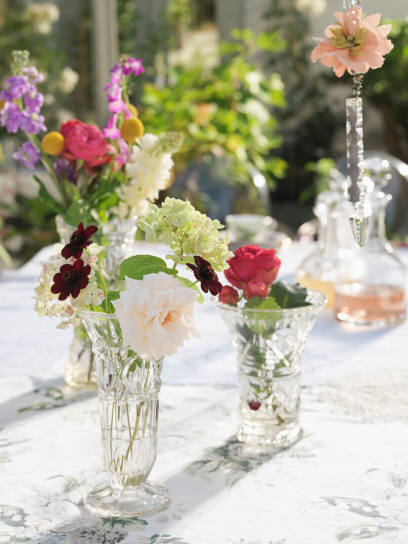 Cut flowers in glass vases on sunlit table Derwent Water, Cumbria, England UK