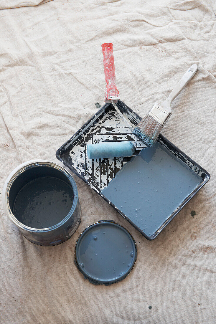 Roller tray with paintbrush on dust sheet in UK home