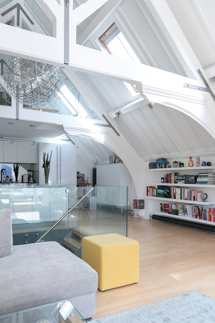 Open plan living room with glass banisters in converted London courthouse UK