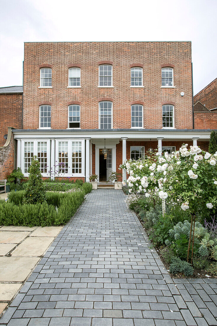 Paved path and roses with Georgian brick facade of Grade II listed Surrey home UK