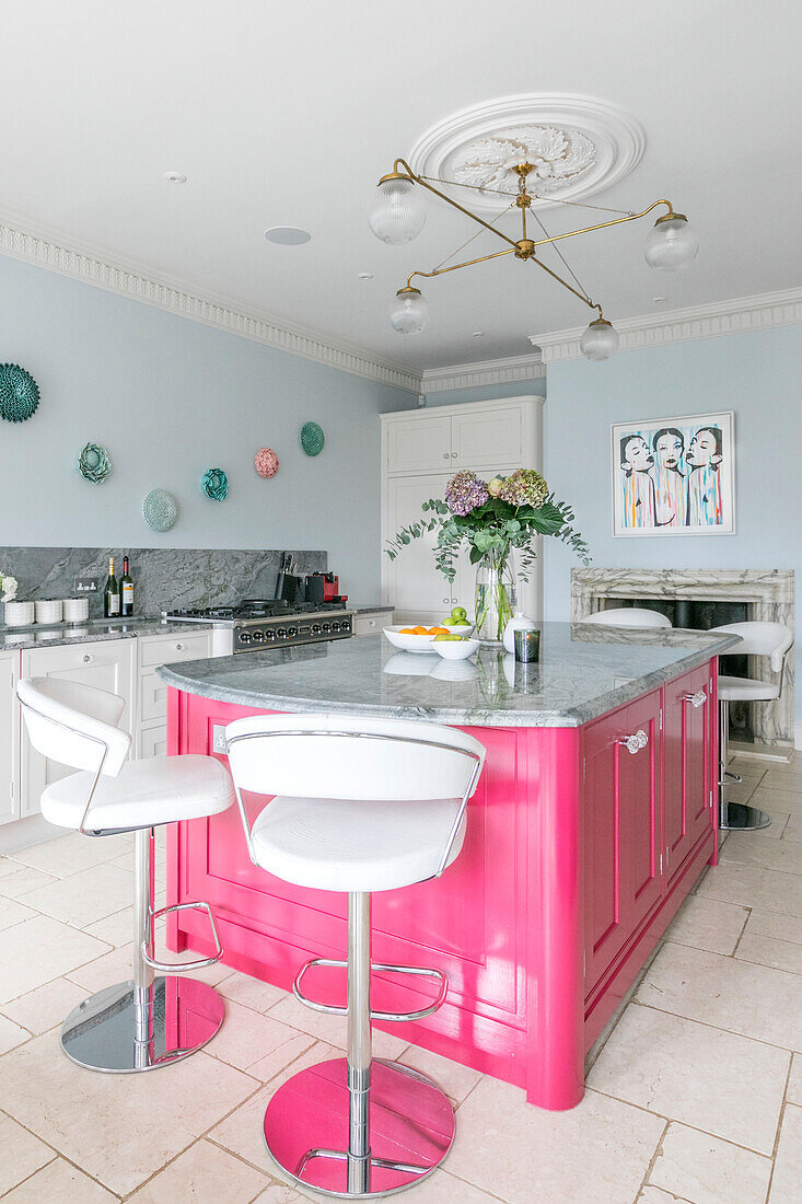 Bright pink island unit in light blue modernised kitchen of Georgian Grade II listed Surrey home UK
