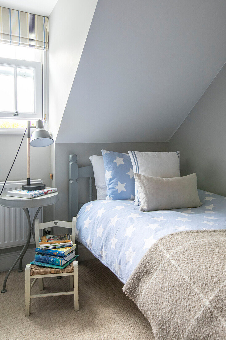 Single bed with bedside table lamp and books in Guildford townhouse Surrey UK