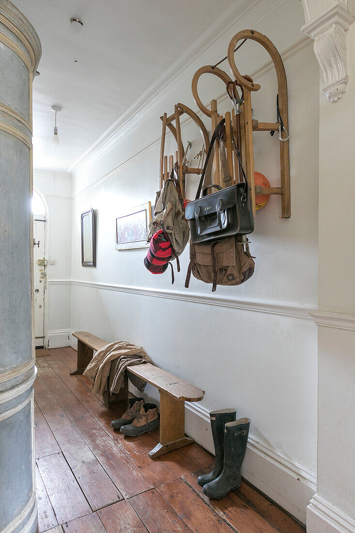 Wall mounted sledges above boots and bench seat in hallway of Winchester home UK