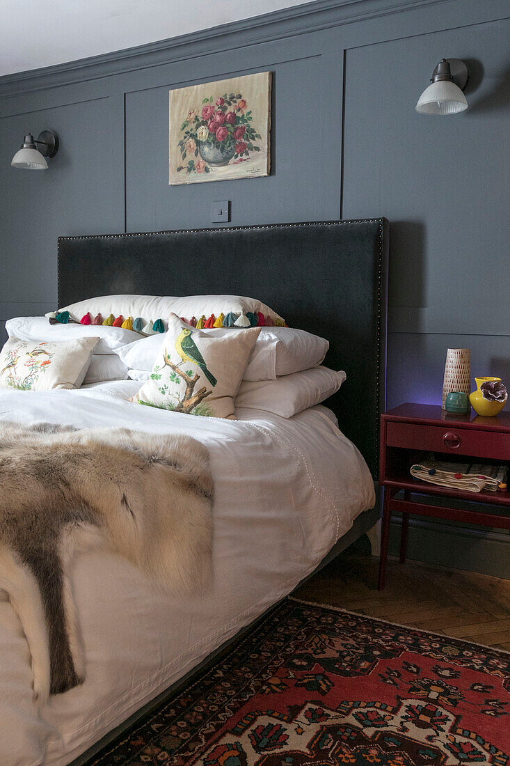 Schwarzes Lederkopfteil mit Wandleuchten auf grauer Vertäfelung in einem Schlafzimmer in Guildford Surrey UK
