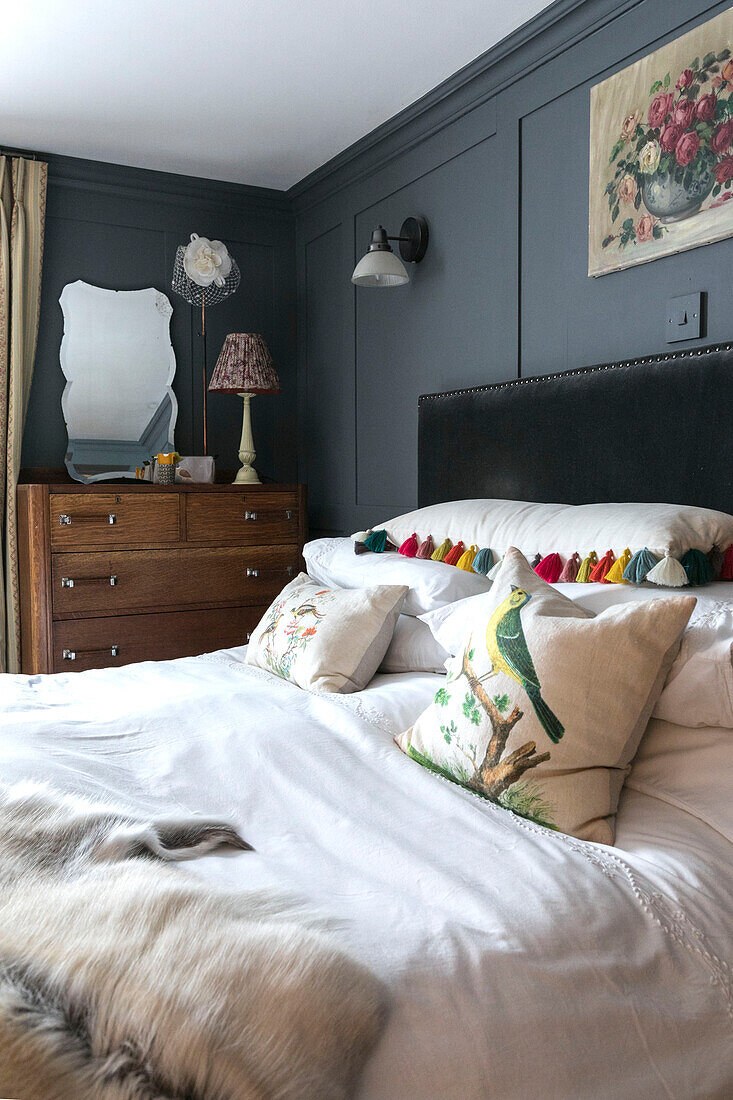 Vintage-Lampe und Spiegel auf Kommode in grau getäfeltem Schlafzimmer in Guildford, Surrey, UK