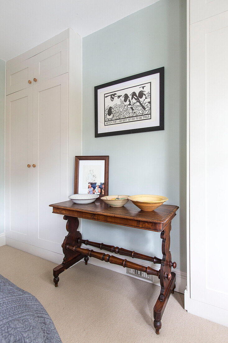Gerahmtes Kunstwerk über einem antiken Holztisch mit Schalen in einem Haus in Reading, Berkshire, England UK