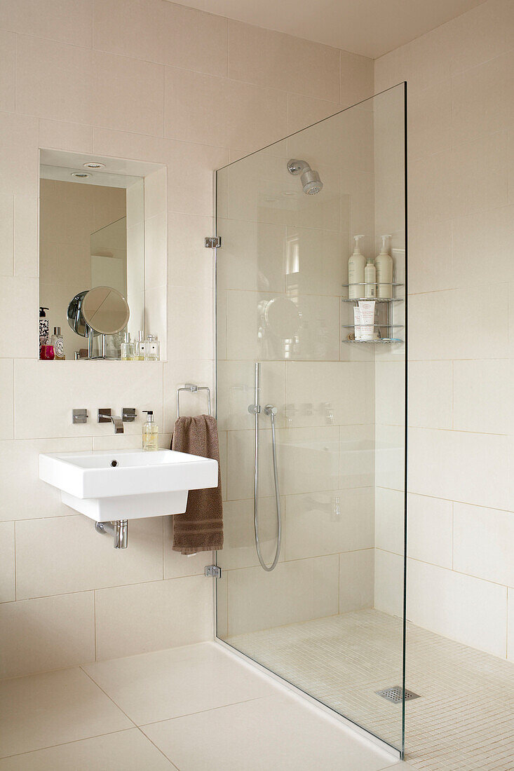 Cream wet room with glass shower cubicle and wall mounted basin
