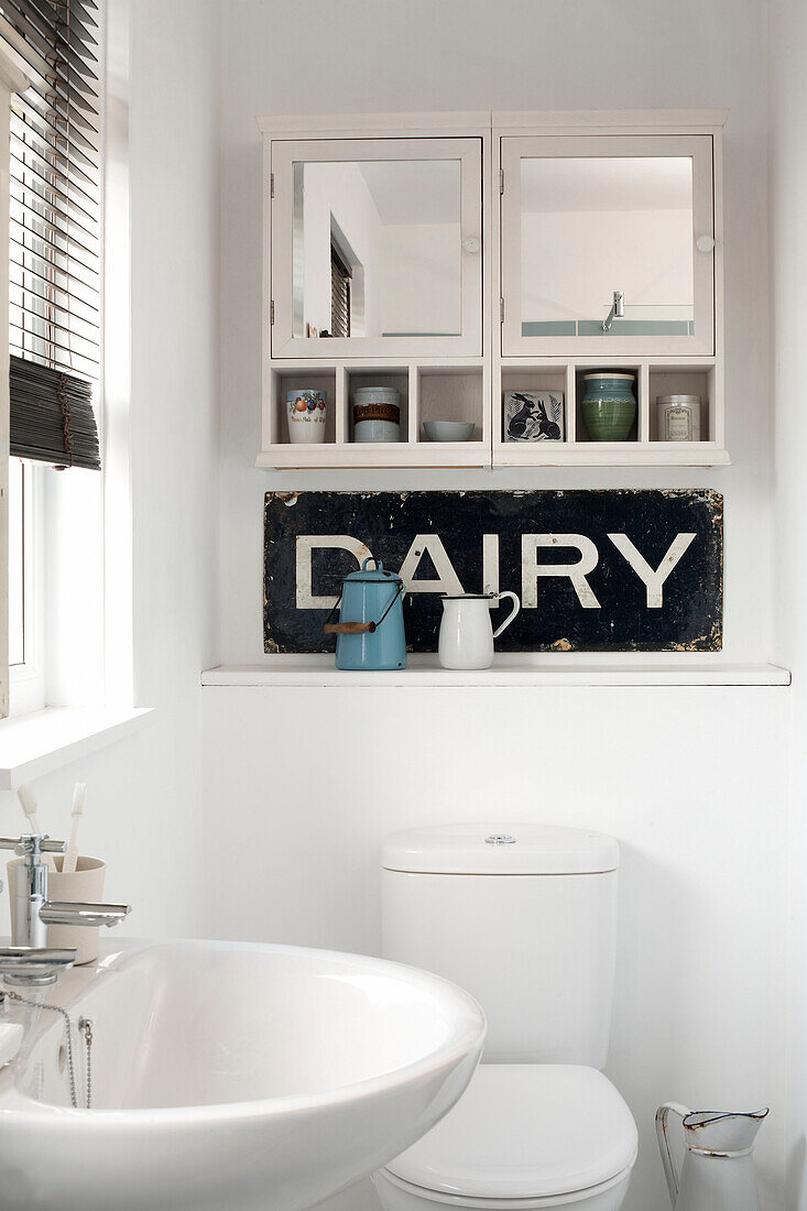 Wall mounted cabinet above salvaged sign in Isle of White bathroom