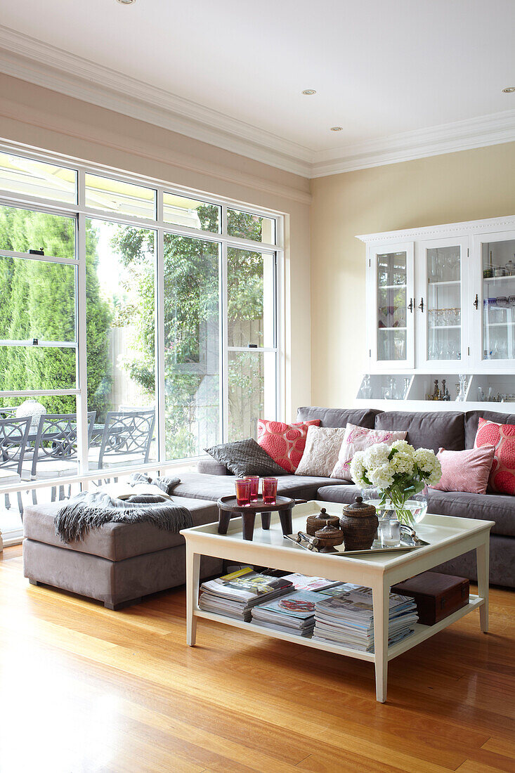 Glass topped coffee table with grey sofa and pink cushions in living room of Sydney home Australia