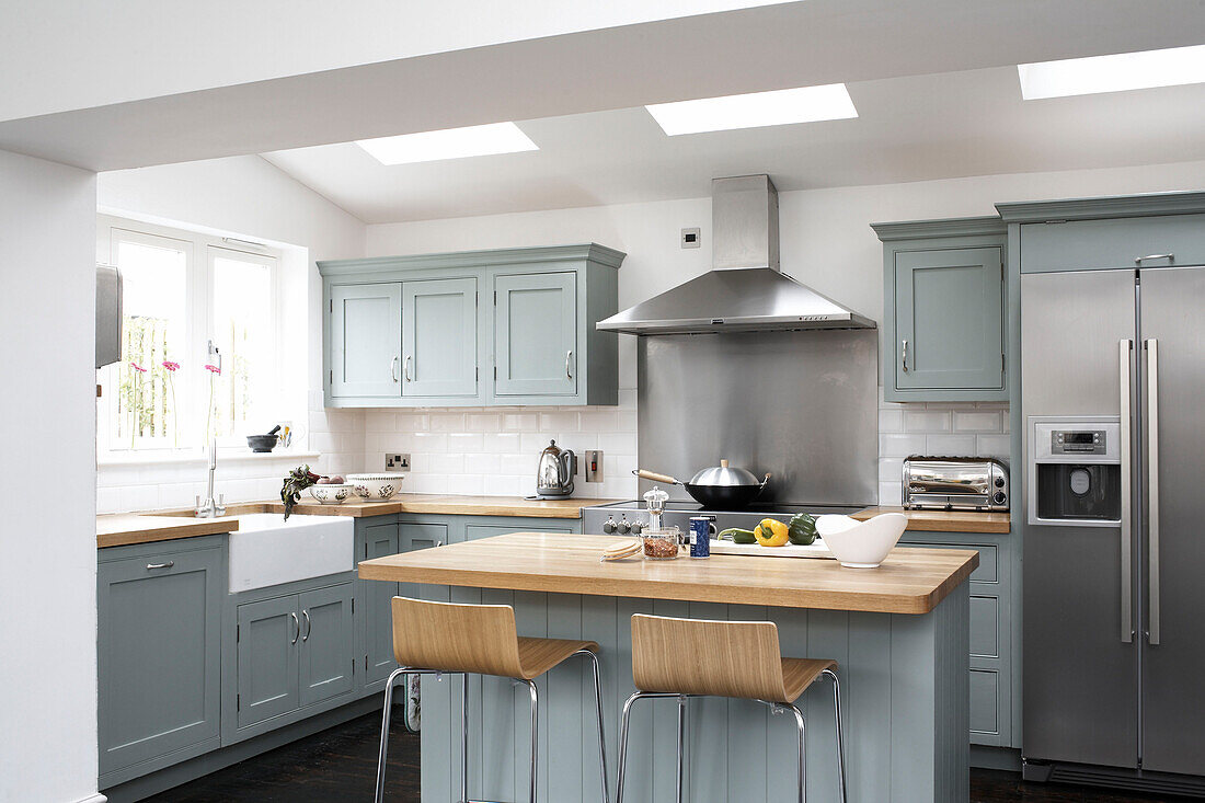 Moderne Küche im Landhausstil mit pastellblauen Schränken und hellen Holzarmaturen