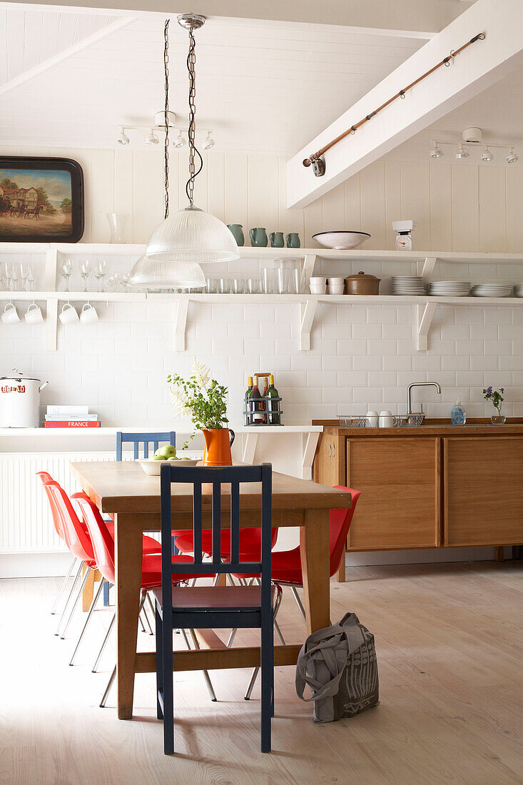 Weiß geflieste Küche mit hölzernem Waschtisch und uneinheitlichem Tisch und Stühlen
