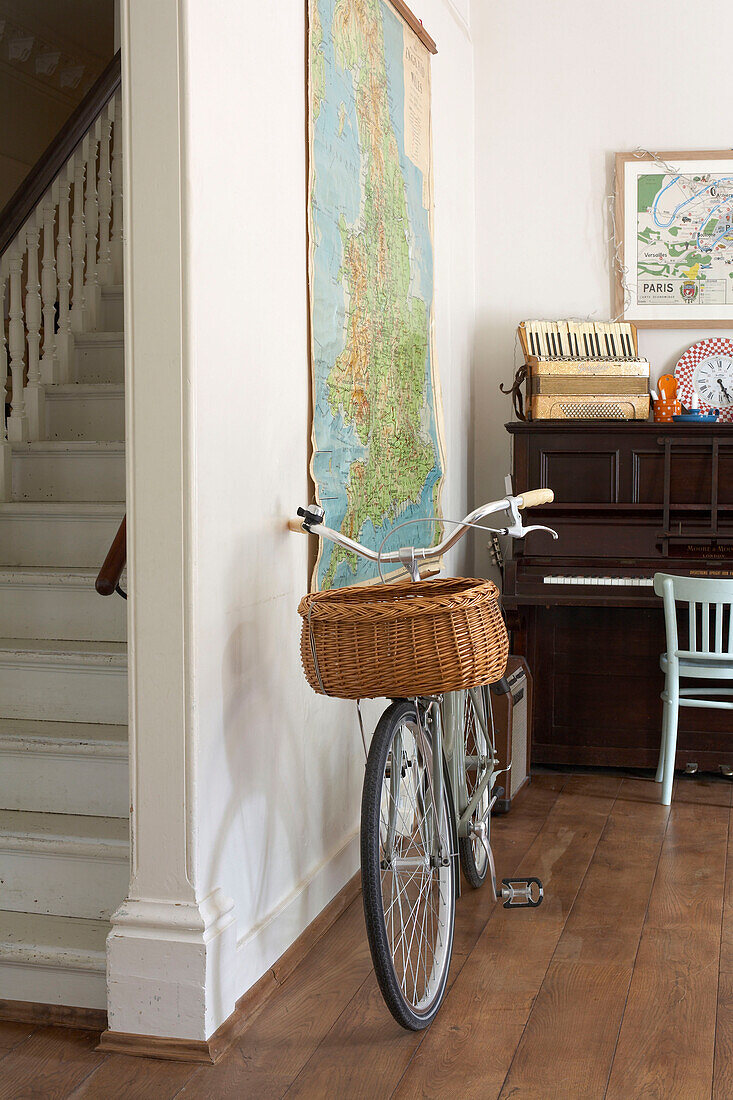 Bicycle with pannier and piano in entrance hall with hanging map
