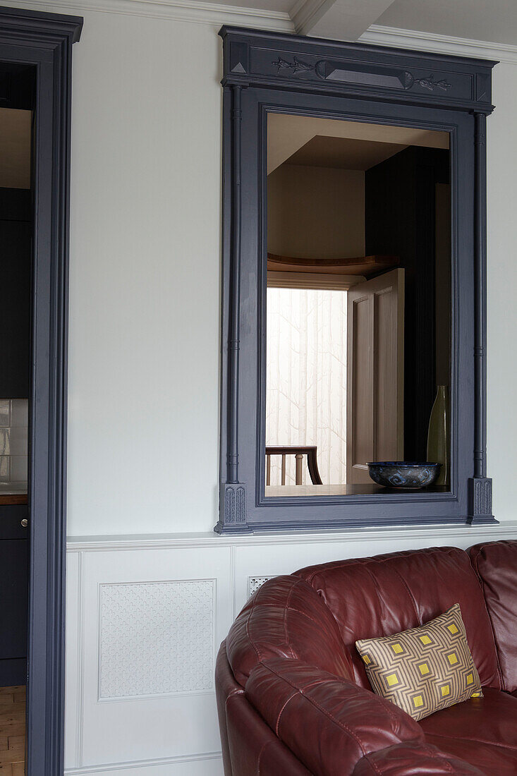 Blau lackierter Spiegelrahmen über einem braunen Ledersofa in einem modernen Haus in Bristol, England, Vereinigtes Königreich