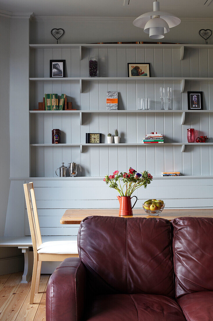 Dining table and painted grey shelving with leather sofa in contemporary Bristol home, England, UK