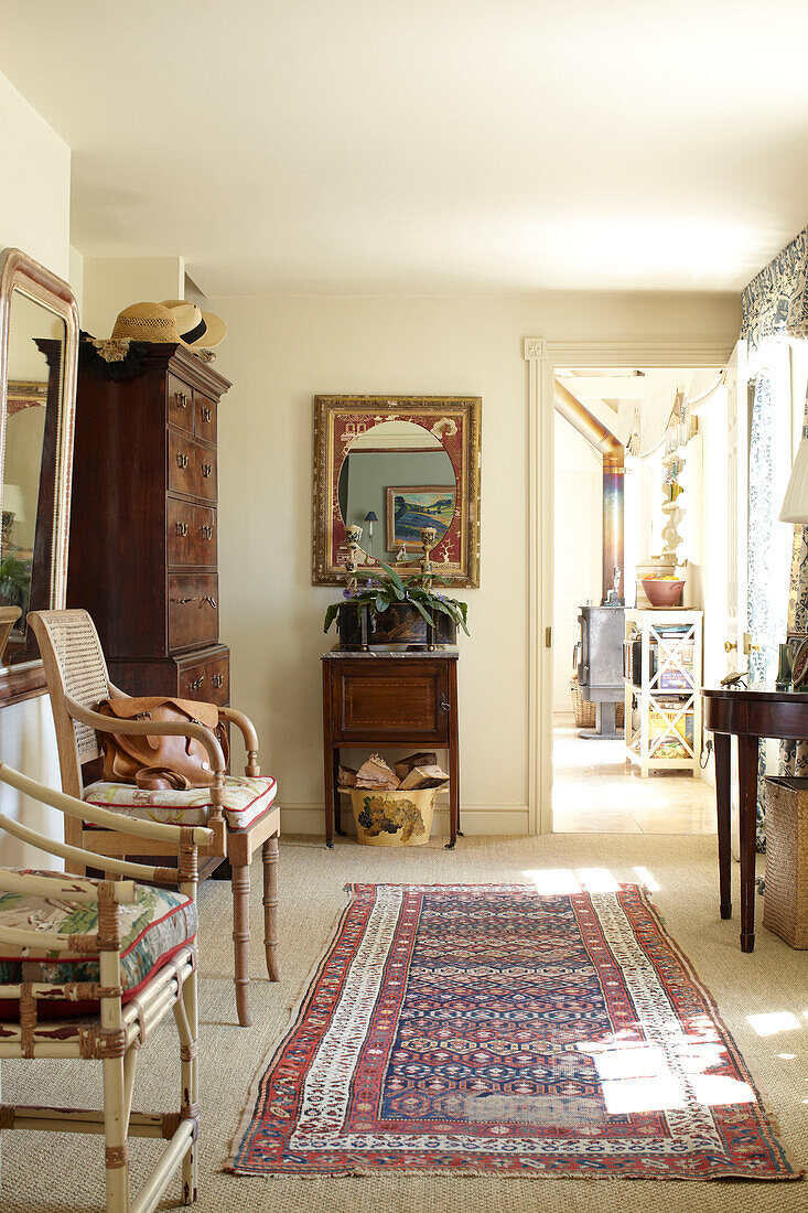 Pair of wicker chairs with patterned rug in hallway of Wiltshire country home, England, UK