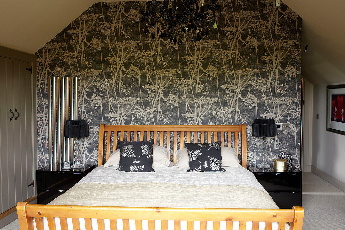 Doppelbett mit Blattmustertapete im Schlafzimmer einer umgebauten Scheune in Somerset, England, UK