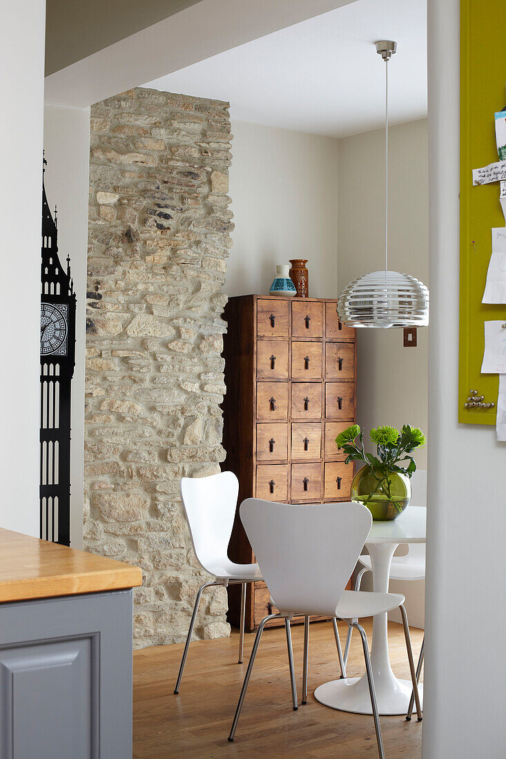 View to dining room with exposed stone wall and wooden storage unit in Coombe cottage, UK