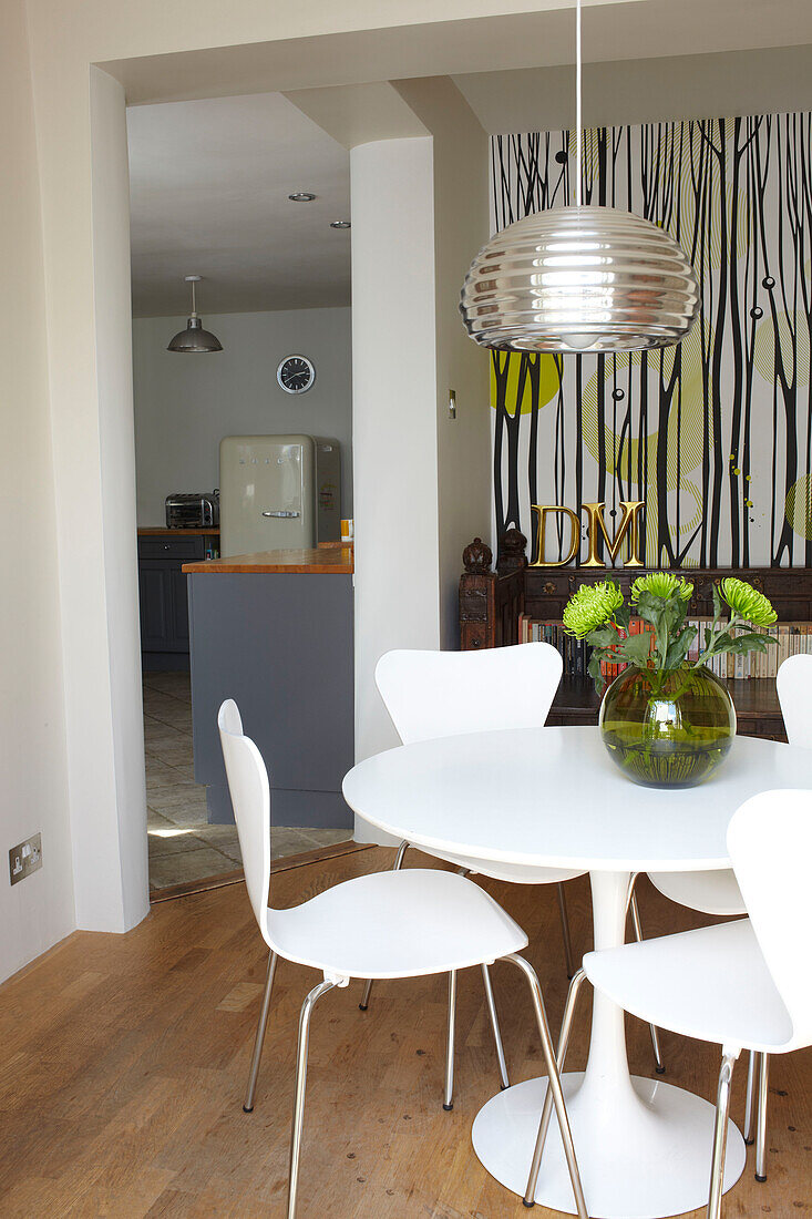 Esstisch und Stühle in einem Raum mit gemusterter Tapete und metallischer Deckenleuchte, Coombe cottage, UK