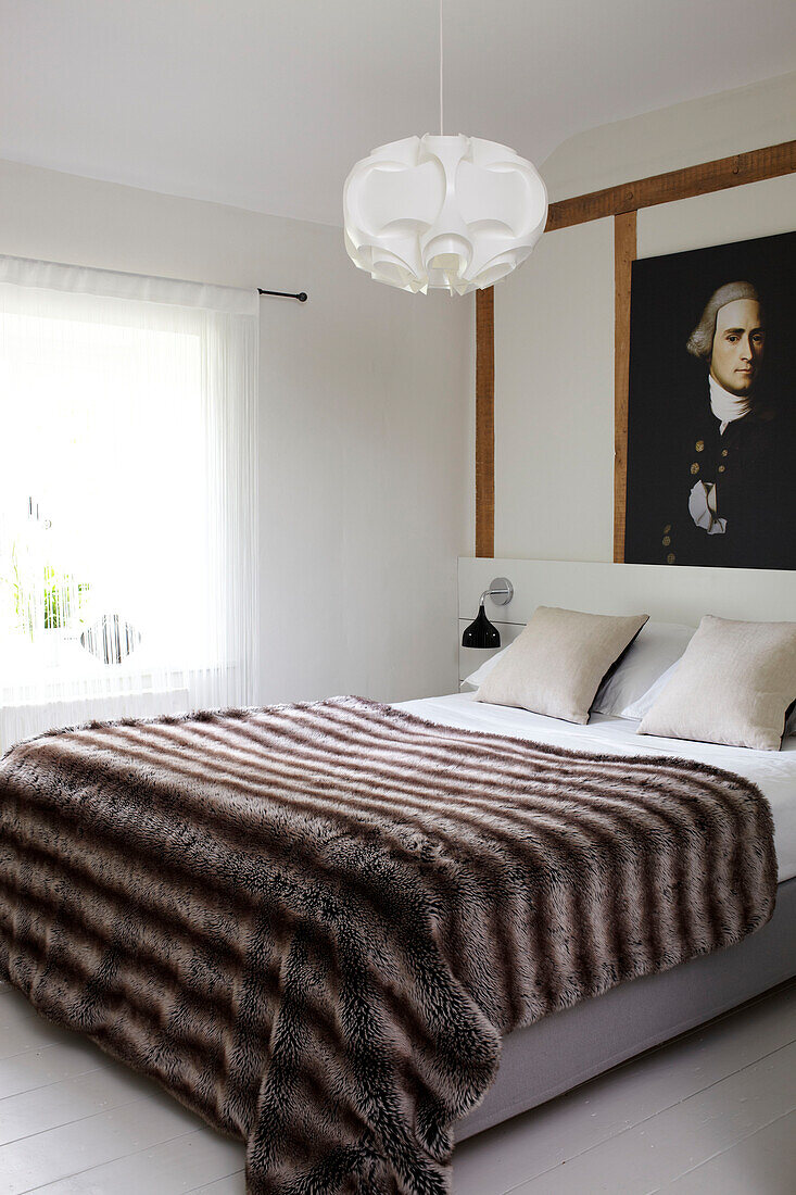 Pelzdecke auf dem Bett in einem modernen Zimmer mit historischem Ölgemälde, Holzrahmen Coombe cottage, England, UK