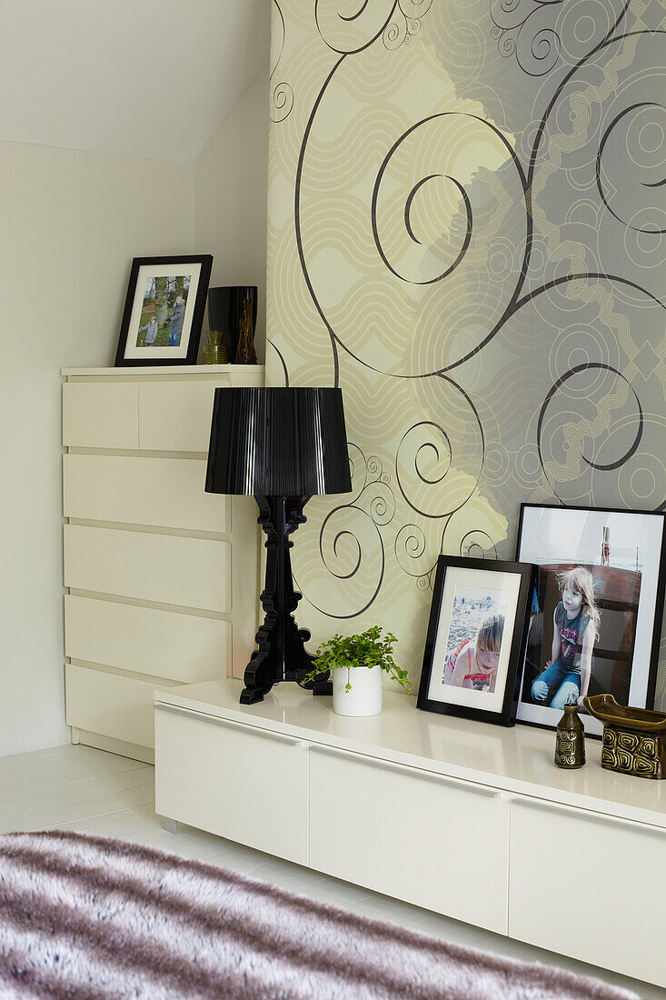 Familienfotos auf dem Sideboard im Schlafzimmer von Coombe mit spiralförmig gemusterter Tapete, England, Vereinigtes Königreich