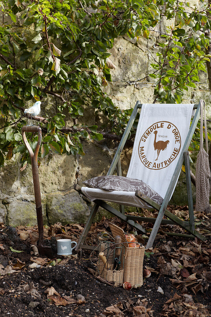Liegestuhl und Spaten mit Werkzeugset im ummauerten Garten, St Lawrence, Isle of Wight, UK